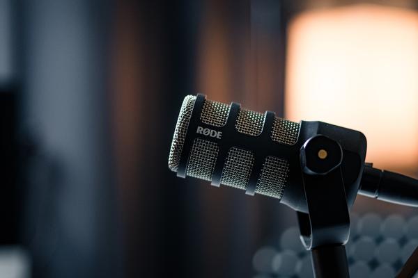A microphone that is set up in a podcast studio, the background is blurred