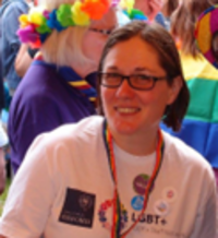 A picture of Helen at a pride parade, wearing an LGBT+ staff network t-shirt