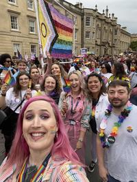 An image of nine members of the LGBT+ Staff Network in the Oxford Pride parade, wearing colourful clothing and holding Pride flags. 